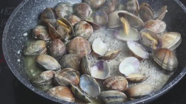 Evde tavada istiridye pişirmek. Beyaz şarapta kaynayan istiridyelerin yakın çekimi.
