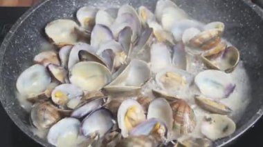 Evde tavada istiridye pişirmek. Beyaz şarapta kaynayan istiridyelerin yakın çekimi.