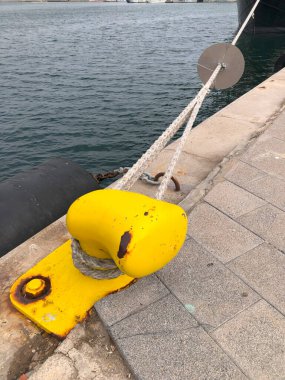 İspanya 'nın Valencia şehrinde bulutlu bir günde, deniz kıyısında iple demirlemiş sarı bir kordon.