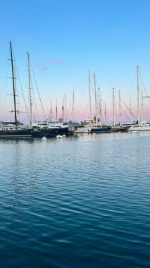 Yelkenli tekneler pembe günbatımında limana yanaştılar..
