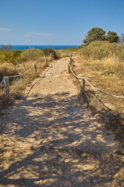 İspanya 'nın Xabia kenti yakınlarındaki Cape Sant Antoni Burnu' nda turist yürüyüş yolu. İp ve ahşap direklerle çevrili, Akdeniz kıyılarına bakan berrak mavi gökyüzü altında.
