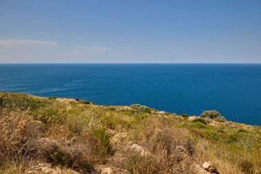 İspanya 'nın Javea kentindeki Cape Sant Antoni' deki kayalıklardan Akdeniz manzarası açık mavi su ve gökyüzü ufka kadar uzanıyor.