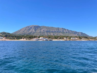 Kıyı kasabası ve dağ manzarası, güneşli bir gün..
