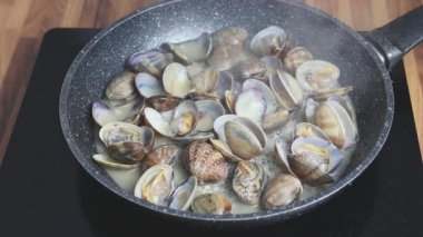 Evde tavada istiridye pişirmek. Beyaz şarapta kaynayan istiridyelerin yakın çekimi.