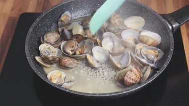 Evde tavada istiridye pişirmek. Beyaz şarapta kaynayan istiridyelerin yakın çekimi.