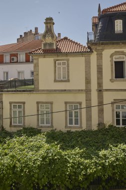 Kırmızı çatılı ve sarmaşıklı tarihi binanın ön cephesine yakın çekim. Covilha, Portekiz - 22 Haziran 2025.