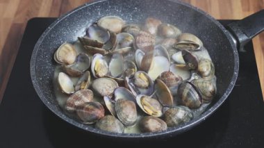 Evde tavada istiridye pişirmek. Beyaz şarapta kaynayan istiridyelerin yakın çekimi.