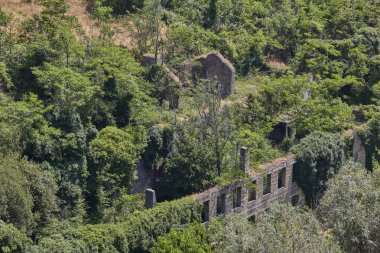 Terk edilmiş taş kalıntıları yamaçta yeşil bitki örtüsüyle kaplanmış..