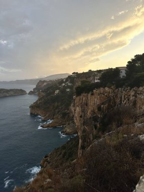 Gün batımında dramatik gökyüzü ile Rocky sahili..