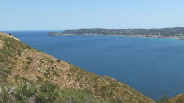 İspanya 'nın Cape Sant Antoni kentindeki kayalıklardan Akdeniz manzarası açık mavi su ve gökyüzü ufka kadar uzanıyor.