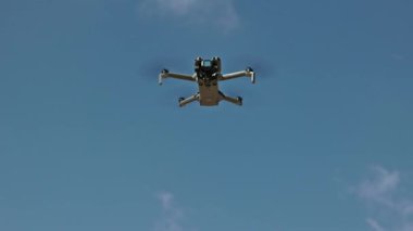 Modern DJI Mini 5 Pro Drone açık mavi gökyüzünde süzülüyor, gelişmiş hava teknolojisi ve kuadkopter tasarımı sergiliyor. Valencia, İspanya - 29 Eylül 2025.