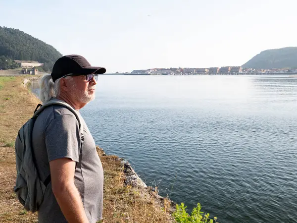 Orta yaşlı havalı bir adam Kuzey İspanya 'da yürüyüş yapıyor ve manzara seyrediyor.