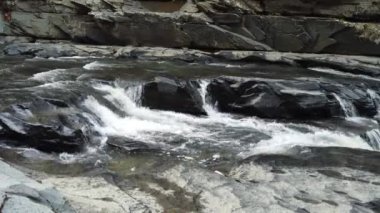 Brezilya 'daki Goias eyaleti Chapada dos Veadeiros' ta Brezilya Cerrado 'sunda siyah kayaları oyan nehir.