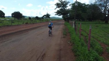 Orta yaşlı bir adam Brezilya kırsalında Goias eyaletinde Brezilya Cerrado 'da dağ bisikleti sürüyor.
