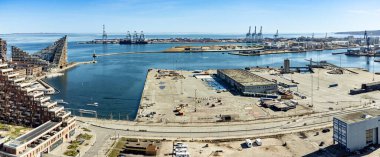 Aarhus liman bölgesinin geniş açısında, arka planda iç limanın girişi ve kargo iskeleleri var. Aarhus Oe yerleşim alanının bir kısmı solda görünür.
