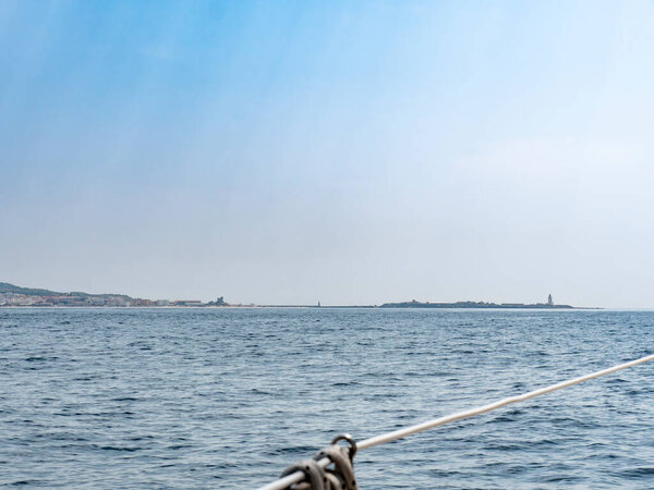 Tarifa island and lighthouse as seen from a sailboat in the straits of Gibraltar. When sailing eastward trough the strait, The Tarifa Island is one of the first things you encounter