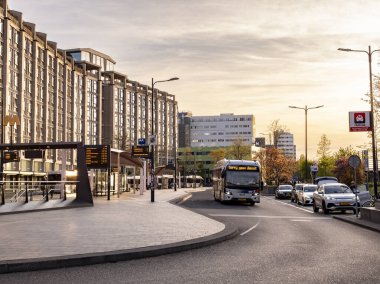Electric bus driving past busstop in Rotterdam, showcasing sustainable public transport in an urban setting. 