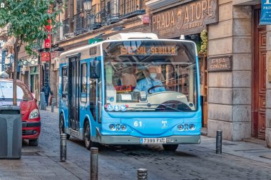 SE Sol-Sevilla güzergahındaki bir belediye otobüsü Madrid 'de dar bir caddede yol alıyor, toplu taşıma araçlarını gösteriyor. Sahne, kalabalık şehirde yayalar ve park halindeki arabalarla günlük hayatı yakalıyor. Madrid, İspanya - 30 Kasım 2021