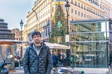 Madrid, İspanya 'da kalabalık bir caddede dikilen bir adam, arka planda Four Seasons Hotel Madrid' in şenlikli dekorasyonları görülüyor, İspanya. Sahne, şehirde kışın özünü yakalar.