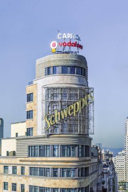 Madrid, İspanya - 30 Kasım 2021: Madrid 'deki ikonik Schweppes binasının Gran Via' daki yakın görüntüsü. Bina, kentin çağdaş siluetinin bir sembolü olan ünlü Schweppes ve Vodafone tabelalarıyla ünlü bir simgedir.