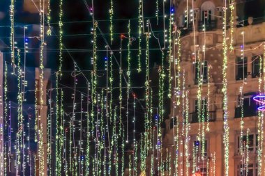 İspanya 'nın merkezi Madrid' de geceyi aydınlatan renkli Noel ışıkları dizileri yukarıdan aşağıya doğru çağlıyor. Şenlikli dekorasyonlar, etrafındaki mimarinin güzelliğini artırıyor ve büyülü bir tatil atmosferi yaratıyor.