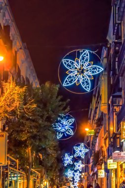 Madrid 'deki şenlikli bir cadde tatil sezonu boyunca çiçek şeklinde mavi Noel ışıklarıyla aydınlandı. Parlak dekorasyonlar gece şehirde canlı ve neşeli bir atmosfer yaratıyor. Madrid, İspanya - 30 Kasım 2021