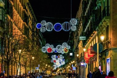 Şenlikli Noel süslemeleri Madrid 'de bir caddeyi karmaşık dairesel tasarımlar ve canlı renklerle aydınlatıyor. Parlak süsler akşamları neşeli bir tatil ortamı yaratır. Madrid, İspanya - 30 Kasım 2021