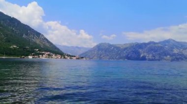 Karadağ 'ın Kotor kenti yakınlarındaki Dobrota köyünden Kotor Körfezi' nin panoramik manzarası. 4K video, 11 saniye. Yaz sahnesi dingin suları, bereketli dağları ve kıyı cazibesini yakalar. Kotor, Karadağ - 18 Haziran 2021