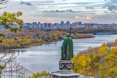 Kyiv, Ukrayna - 27 Ekim 2023: Kyiv 'deki Dnipro Nehri' ne bakan Aziz Volodymyr heykelinin arkasından bir manzara. Sonbahar renkleri manzaralı şehir manzarasını güzelleştiriyor, tarihi doğal güzelliklerle harmanlıyor.