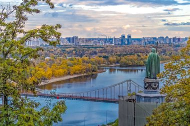 Kyiv, Ukrayna - 27 Ekim 2023: Kyiv 'deki Volodymyrska Tepesi' nden Dinyeper Nehri 'ne bakan Aziz Volodymyr heykelini gösteren sakin bir manzara. Sonbahar ağaçları manzaraya sıcak bir renk katar, uzaktaki şehir manzarasıyla.
