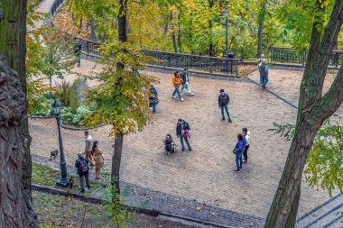 Kyiv, Ukraine - October 27, 2023: Overhead view of people enjoying a walk through Volodymyrska Hill in Kyiv surrounded by lush autumn foliage. The park's scenic pathways provide a serene escape within the city clipart