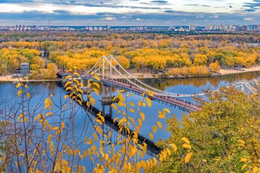 Ukrayna 'nın başkenti Kyiv' deki Dnipro Nehri 'ndeki yaya parkı köprüsünün sonbahar manzarası, canlı sarı ve turuncu yapraklarla çevrili. Huzurlu manzara, başkentte sakin bir sonbahar gününün özünü yakalıyor.