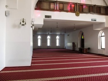Kyiv, Ukrayna - 8 Ekim 2018: Kyiv 'deki Ar-Rahma Camii' nin kırmızı halı, masa ve beyaz duvarlı büyük boş bir salon. Müslümanların ibadethanesinde dini semboller ve bir sürü lamba var.