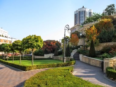 Kyiv, Ukraine - October 8, 2018: Beautiful well-kept Heydar Aliyev Park in Kyiv on an autumn sunny day. Neat alleys, oriental plants, well-groomed lawns, street lamps and a copy of Baku fortress wall clipart