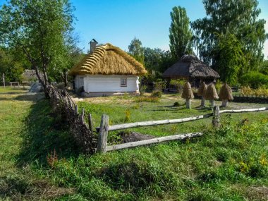 Ukrayna, Pyrohiv (Kyiv) - 17 Eylül 2017: Beyaz duvarları ve açık yaz-sonbahar gününde yeşilliğin arka planında sazdan bir çatısı olan Ukrayna geleneksel kırsal evi. Pirogovo 'daki Halk Mimari ve Yaşam Müzesi' nin antik bir sergisi.