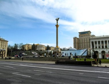 Kyiv, Ukrayna - 31 Aralık 2017: Merkezi Ukrayna Bağımsızlık Anıtı ile Maydan Nezalezhnosti - yan görüş. Kyiv 'de kar olmayan ılık bir kış, çıplak ağaçlar, mavi gökyüzü ve meydanda kalın giysiler içinde insanlar.