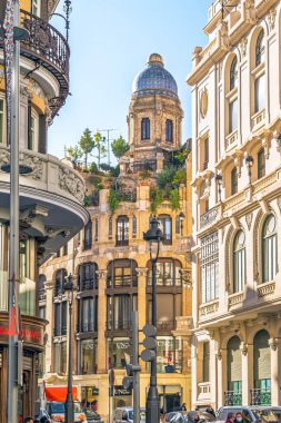 Madrid, İspanya - 30 Kasım 2021: Gran Via caddesinden dikey manzara Madrid 'deki kendine özgü kubbesi ve yemyeşil çatı bahçesiyle Casa de los Portugueses' i yakalıyor. Bu tarihi binada 20. yüzyılın başlarında mimari detaylar var.