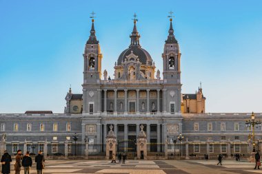 Madrid, İspanya - 30 Kasım 2021: Madrid 'deki Almudena Katedrali' nin önündeki Plaza de la Armeria Meydanı 'ndaki insanlar. Madrid Kraliyet Sarayı 'ndan Katolik Kilisesi manzarası