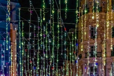 Parıldayan ışıkların şenlikli dizileri 2021 Noel sezonunda İspanya 'nın Madrid kentindeki bir binanın ön cephesinde büyülü bir sahne oluşturur. Parlak ışıklar şehrin mimarisinin güzelliğini vurguluyor, geceyi tatil neşesiyle dolduruyor.