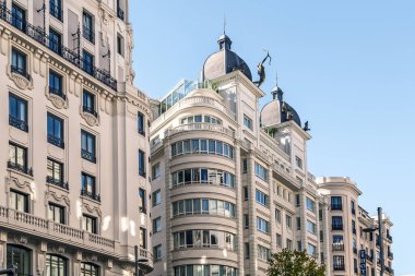 Madrid, İspanya - 30 Kasım 2021: Madrid 'deki Gran Via caddesi boyunca birden fazla bina, modern ve klasik mimari tarzların bir karışımını sergiliyor. Geniş pencereli zarif cepheler, karmaşık balkonlar ve çatı heykelleri.