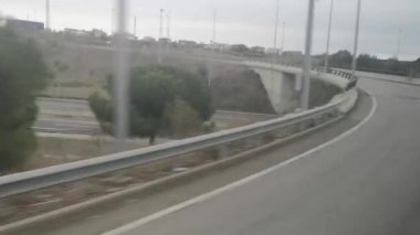 Otobüs penceresinden İspanya 'da Lleida' dan Girona 'ya bir yolculuk sırasında kasvetli bir sonbahar sabahı manzarası yakalar. Video 28 saniye. Sahnede otoyollar, köprüler, tarlalar ve yuvarlanan tepelerdeki köyler yer alıyor.