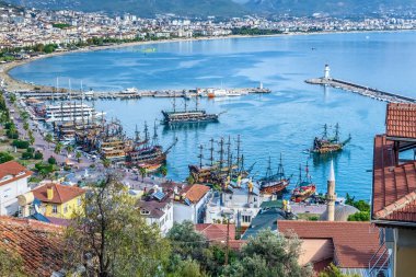 Türkiye 'nin limanı boyunca geleneksel korsan gemilerinin demirlediği Alanya limanının manzarası. Kıyı şeridi, dağlarla çevrili bir deniz feneriyle uzanıyor. Alanya, Türkiye - 24 Ekim 2020