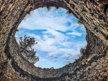 Türkiye 'nin Alanya Şatosu' ndaki taş bir kuleden gökyüzüne bak. Harabeler, eski tuğlalarla yukarıdaki canlı bulutlar arasında çarpıcı bir tezat oluşturuyor.