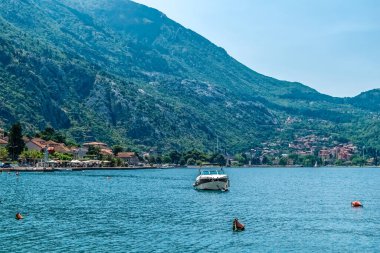 Karadağ 'ın Kotor Koyu' nun sakin sularında yüzen ve arka planda dağlara karşı kurulmuş pitoresk bir kasaba olan Kotor 'u gösteren sakin bir manzarası. Bu kıyı kasabasının doğal güzelliği hayret verici.
