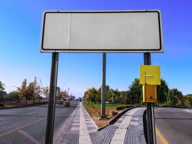 Ankara 'da (Türkiye) bir şehir yolunun arka planında boş beyaz yol tabelası. Güneşli bir yaz-sonbahar gününde, bir kasaba caddesinde bir yol işaretinin boş şablonu.