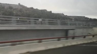 İspanya 'nın Katalonya kentindeki hareket halindeki bir otobüsün camından sonbahar manzarası ve otoyol görünüyor. 53 saniyelik video. Manzara hızla değişirken arabalar geçiyor. Cam yansıması seyahat deneyimine derinlik katıyor.