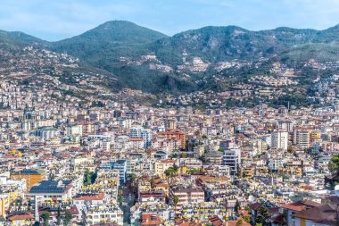Türkiye 'nin Alanya kentinin panoramik hava manzarası, yeşil dağlarla çevrili geniş bir şehir manzarası. Şehir manzarası konut binaları ve doğal tepelerin bir karışımını sergiliyor. Alanya, Türkiye - 24 Ekim 2020