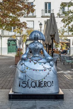 Madrid, İspanya - 30 Kasım 2021: Plaza de Santa Ana, Madrid 'deki Menina heykelinin dikey görünümü, bağlılığı simgeleyen renkli kilitlerle süslenmiştir. Bu çağdaş sanat eseri canlı kareye eşsiz bir cazibe katıyor.