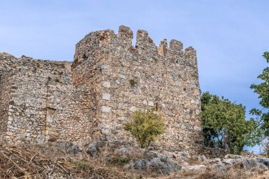 Türkiye 'deki Alanya Kalesi' nin antik taş kulesinde ortaçağ mimarisi sergileniyor. Yıpranmış duvarlar ve çevreleyen yeşillikler kalenin tarihsel önemini vurguluyor.