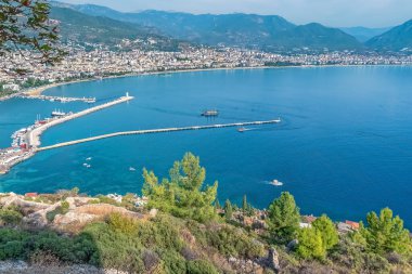 Türkiye 'nin Alanya Şatosu' ndan Alanya Marina ve limanı, Akdeniz 'e uzanan tekne ve uzun bir iskele. Manzaralı kıyı kasabası dağlarla çevrili ve yemyeşil.